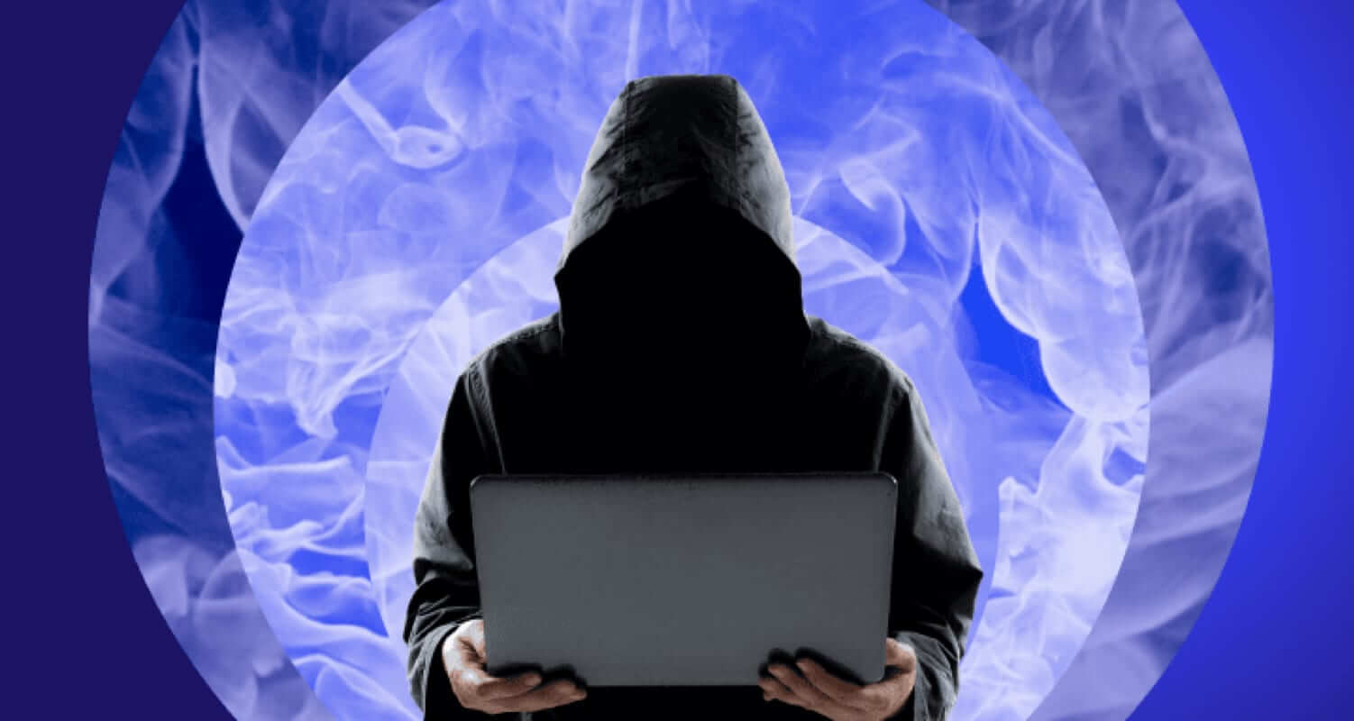 Man holding a laptop with a hood hiding his face