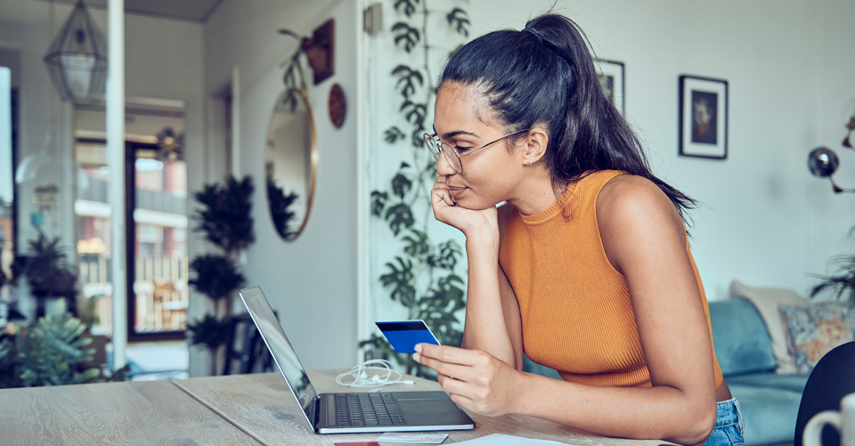 Woman using a laptop and holding a financial card