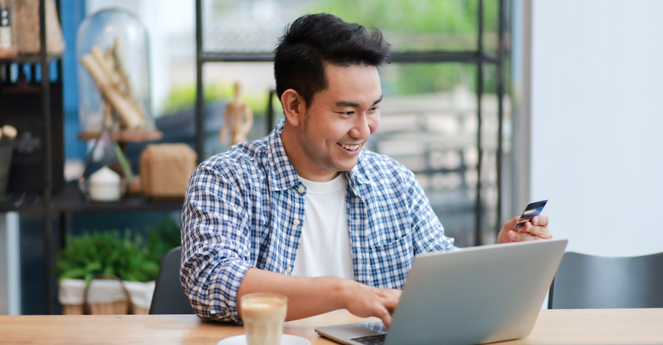 Man using a laptop and holding a financial card