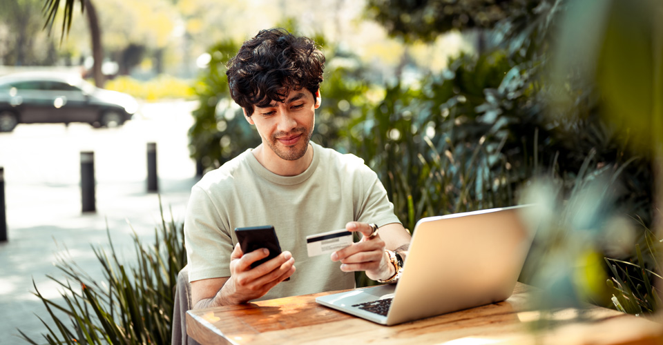 Man sitting at a table holding a phone and financial card