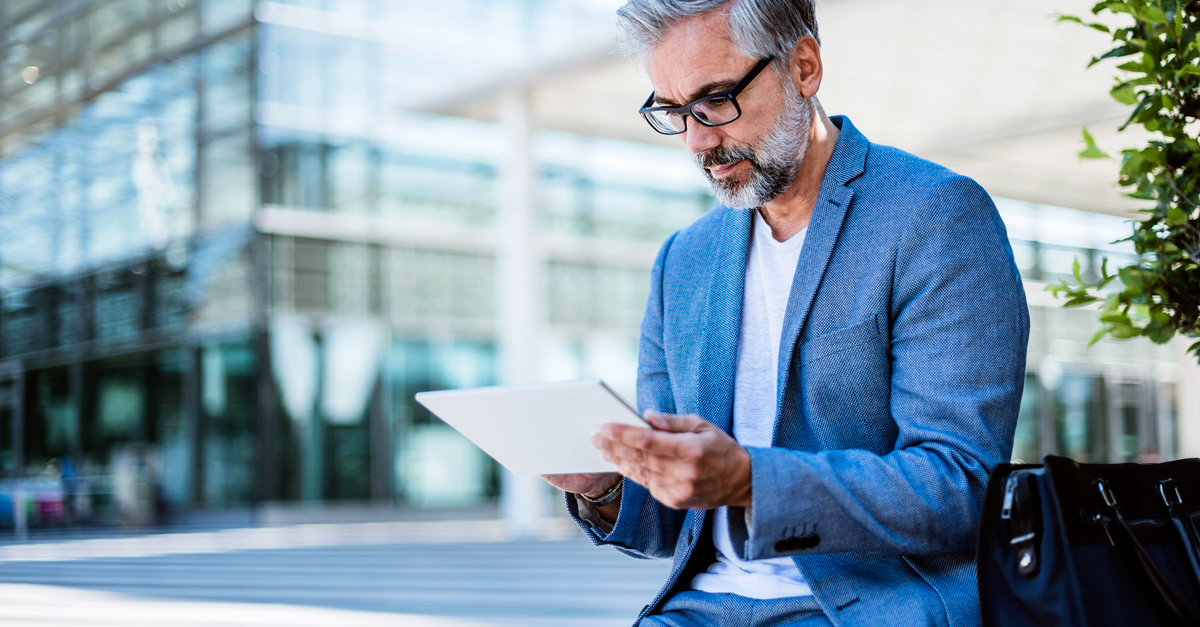 middle-aged man in glasses looking down at tablet