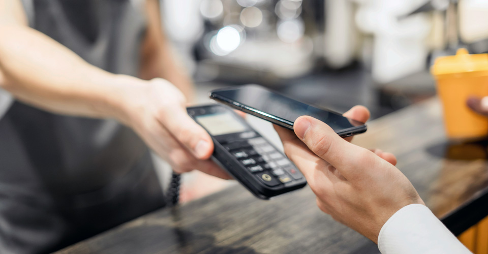 一名男性在咖啡店手持手机进行 NFC 付款的特写镜头