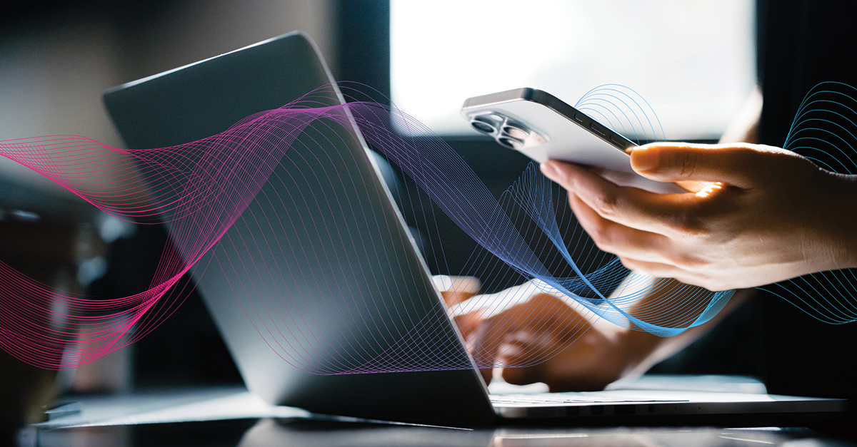 close-up of hands on laptop and holding mobile device