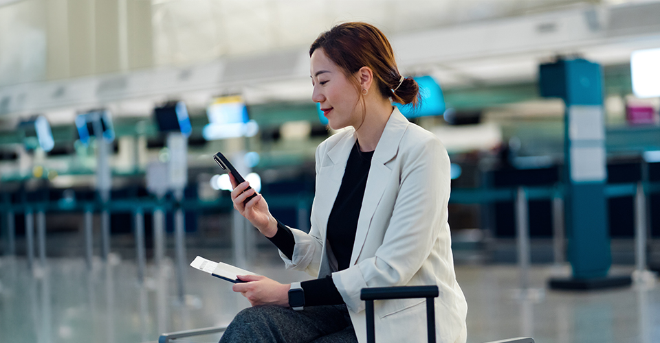 Person seated with luggage using a smartphone in an airport terminal
