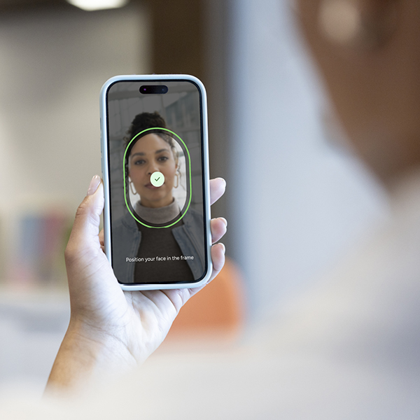 Person holding a smartphone displaying a facial verification scan for identity authentication