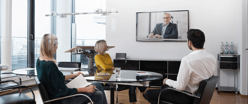 Coworkers in a conference room looking at tv screen