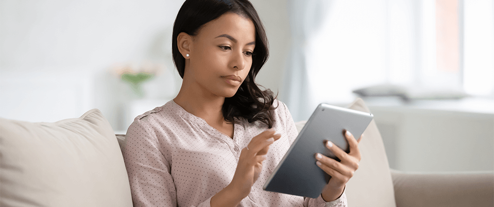 Woman sitting on the couch looking at a tablet