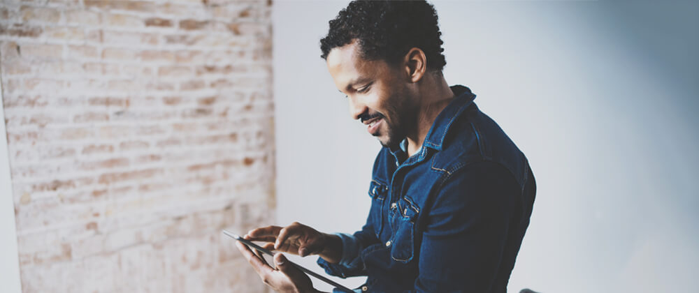 man looking down and tapping on tablet