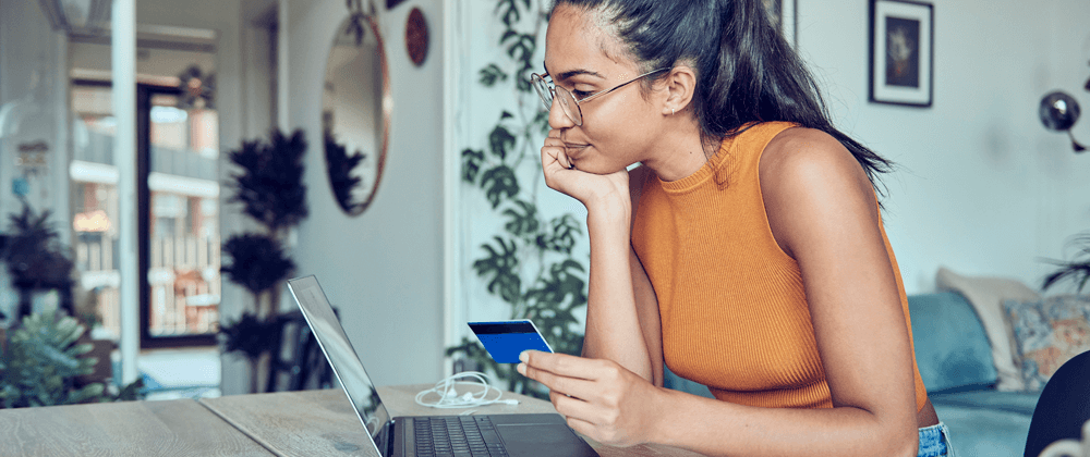 Woman holding a financial card and using a laptop