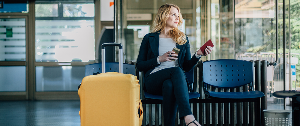 Woman sitting down and holding a phone and passport