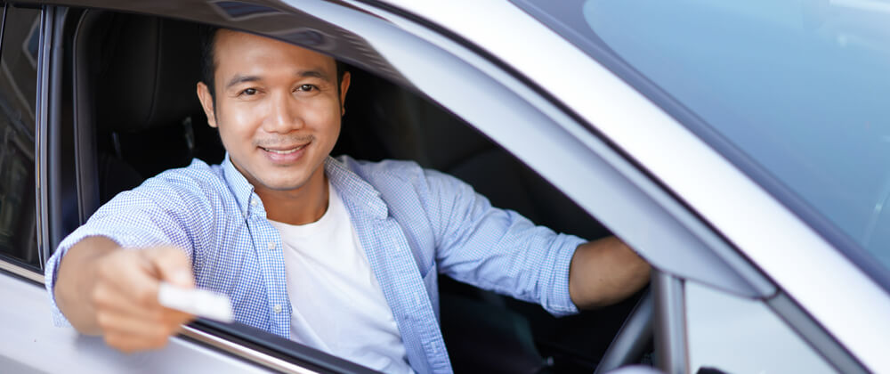 man in car holding out card for contactless payment