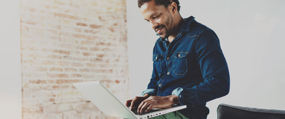 man sitting on couch working on laptop